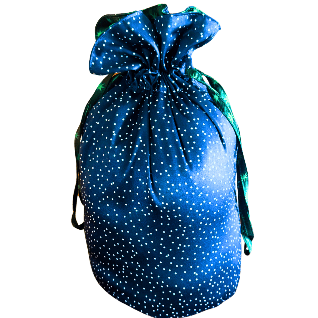 A blue reusable drawstring fabric gift bag pouch decorated with white polka dots and a green satin drawstring, isolated on a white background.