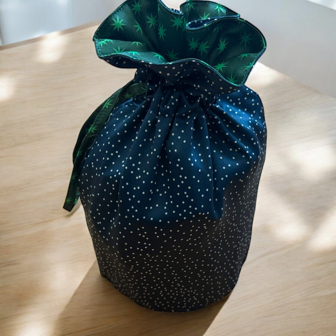 Dark green drawstring bag with star pattern on a light wooden surface