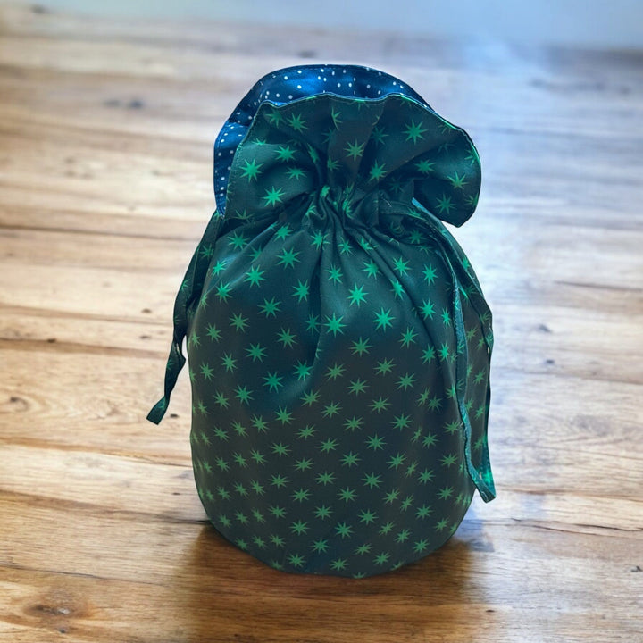Green drawstring bag with star pattern on a wooden surface